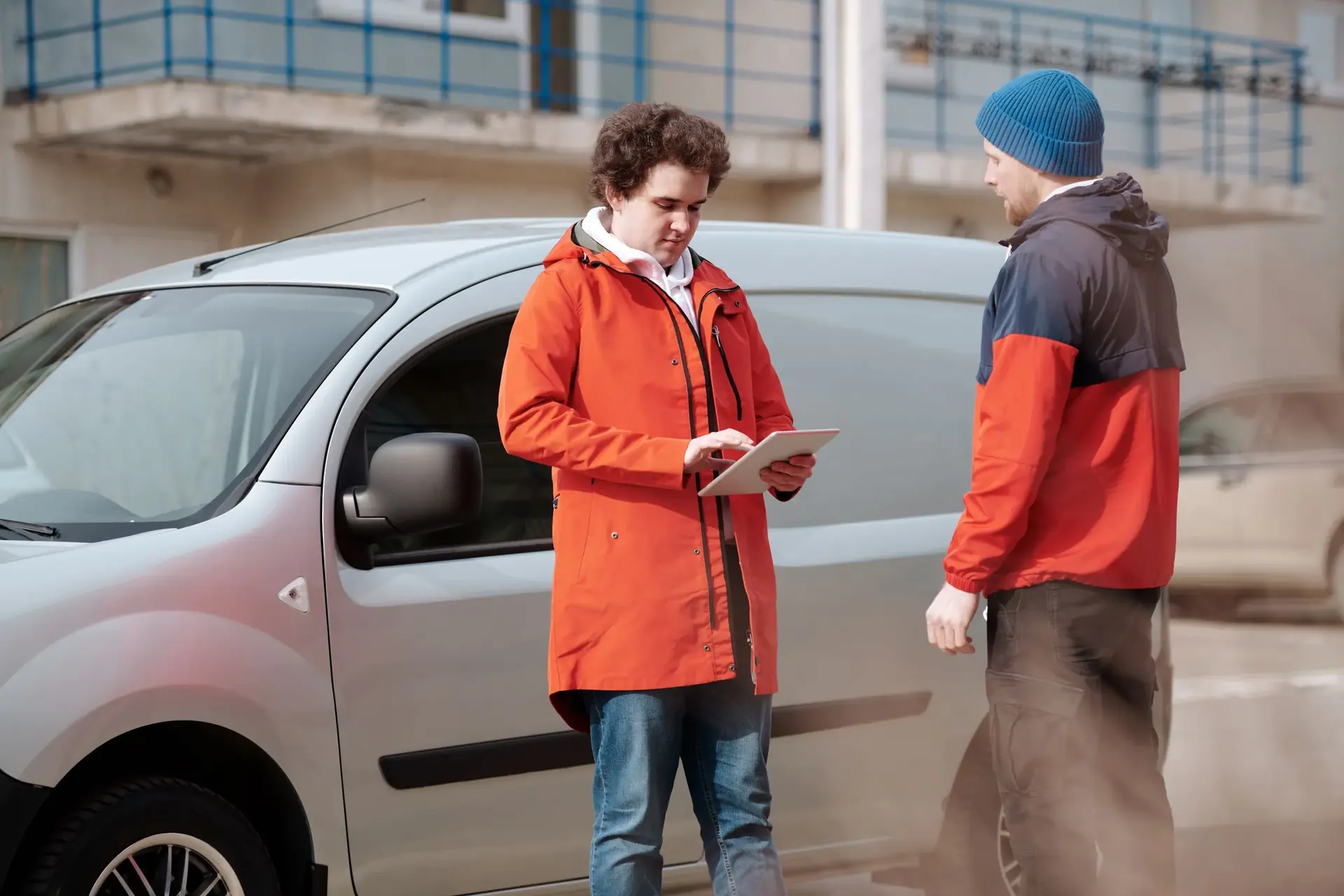 Un technicien consulte sa tablette devant sa camionnette, avec un client, dans une rue