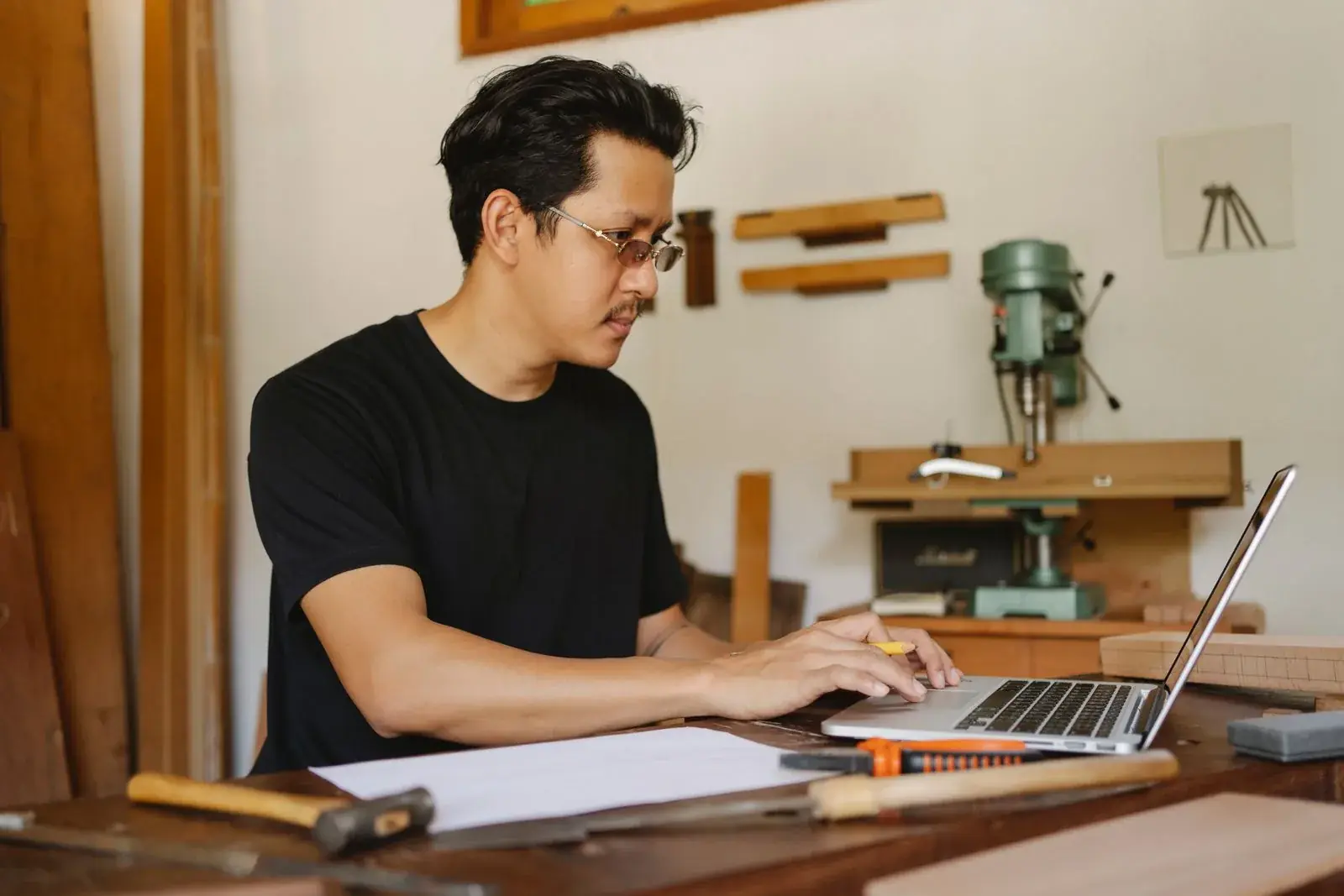 Un artisan saisit des données sur son ordinateur portable, à l'établi de son atelier