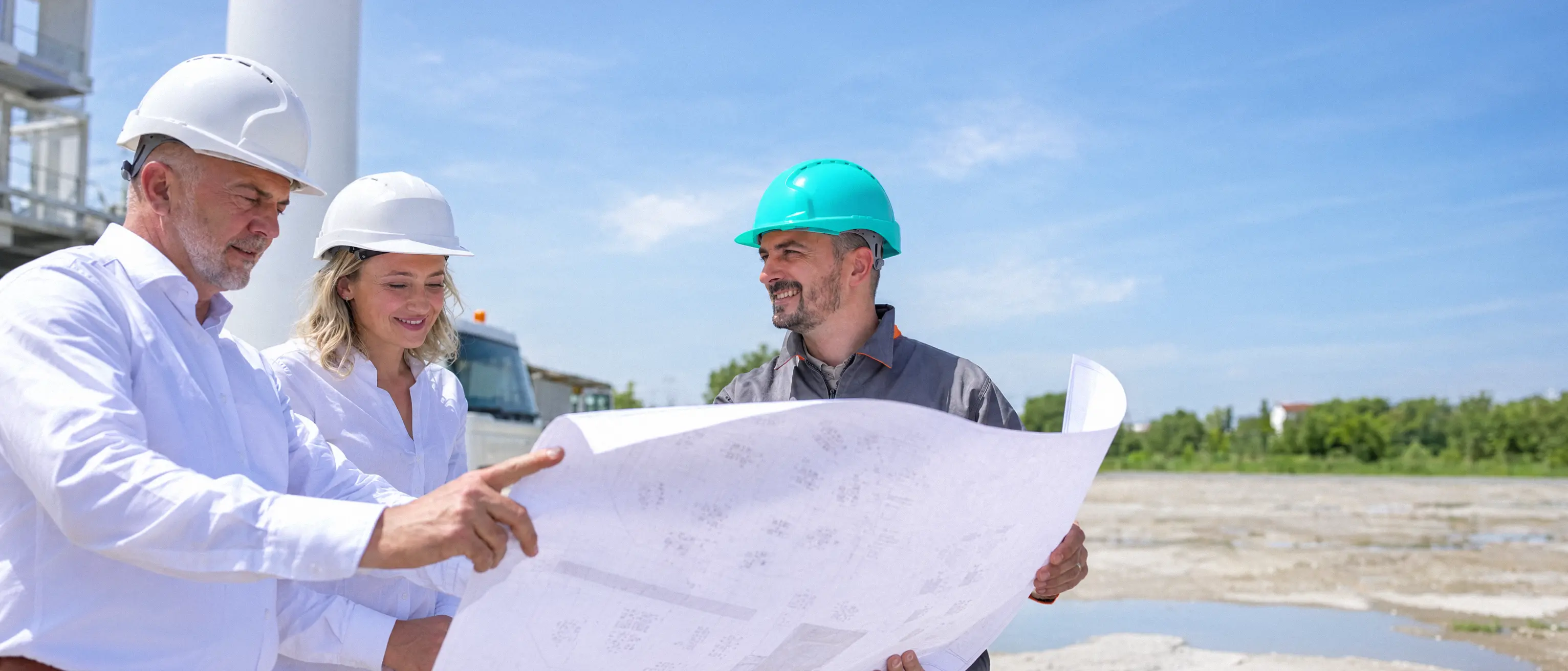 Trois professionnels du bâtiment lisent un plan sur un chantier
